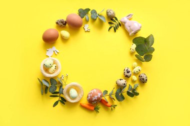 Paskalya yumurtalarından, okaliptüs dallarından ve sarı arka planda dekordan yapılmış çerçeveler.