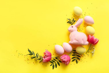 Paskalya yumurtalarından, dekoratif tavşanlardan, lale çiçeklerinden ve sarı arka planda yeşil yapraklardan yapılmış çerçeveler.