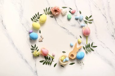 Paskalya yumurtalarından, çiçeklerden, yeşil yapraklardan ve mermer arkaplandaki dekordan yapılmış çerçeve