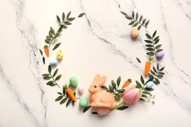 Paskalya yumurtalarından, çiçeklerden, yeşil yapraklardan ve mermer arkaplandaki dekordan yapılmış çerçeve
