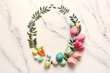 Paskalya yumurtaları, çiçekler, yeşil yapraklar ve mermer arka planda dekoru olan kompozisyon