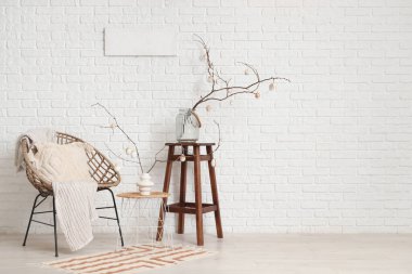 İçinde ağaç dalları olan vazolar ve şenlikli oturma odasındaki sehpalarda paskalya yumurtaları.