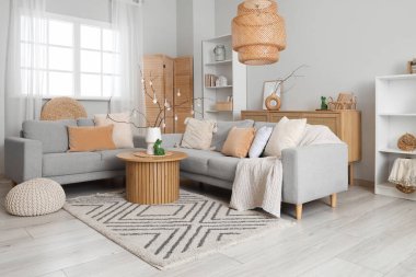 Şenlikli oturma odasındaki sehpanın üzerinde ağaç dalları ve Paskalya yumurtaları olan vazo.