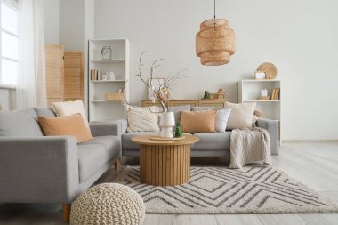 Şenlikli oturma odasındaki sehpanın üzerinde ağaç dalları ve Paskalya yumurtaları olan vazo.