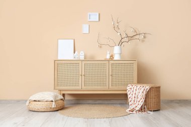 Ağaç dallı vazo ve bej duvarın yanındaki ahşap dolapta Paskalya yumurtası.