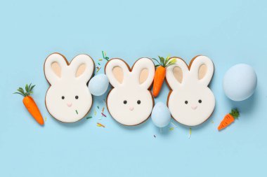 Yumurtalı kompozisyon, dekoratif havuçlar ve mavi arka planda tavşan şeklinde Paskalya kurabiyeleri.