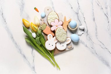 Lale çiçekli kompozisyon, kesim tahtası ve mermer zemin üzerinde Paskalya kurabiyeleri