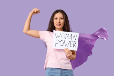 Genç Asyalı kadın, süper kahraman pelerini ve eflatun kaplamalı plaketi var.