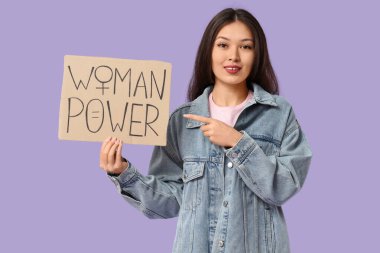 Genç Asyalı kadın leylak arkaplanındaki tabelayı işaret ediyor