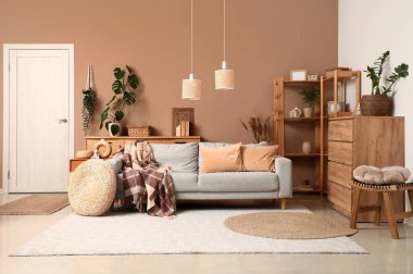 Çekmece sandığı, oturma odasının içinde ekoseli rahat bir kanepe ve puf.