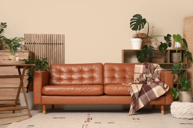 Konforlu kanepe, ev çiçekleri ve oturma odasının içindeki masa.