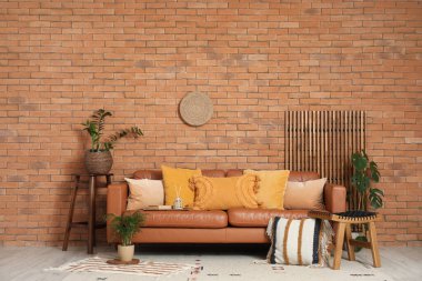 Rahat bir kanepe, minderli bir tabure ve oturma odasının iç tarafında bitkiler.