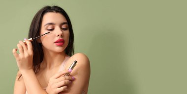 Yeşil arka planda zarif maskarası olan genç ve güzel bir kadın.