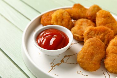Lezzetli nugget tabağı ve yeşil ahşap masada bir kase ketçap.