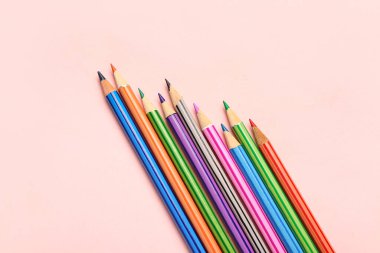 Pembe arka planda renkli kalemler grubu