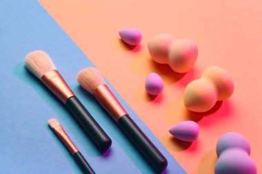 Renkli arkaplanda makyaj süngerleri ve fırçalar