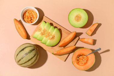 Wooden board with tasty ripe melons on orange background clipart