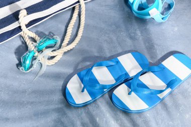 Grunge Blue arka planında plaj aksesuarları olan şık bayan terlikleri.