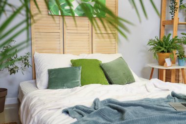 Şık yatak odasında yeşil yastıklı büyük bir yatak.