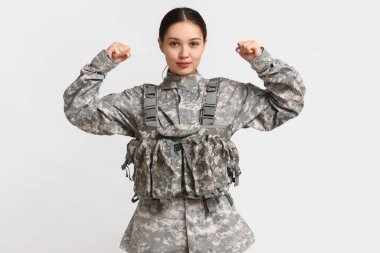 Young female soldier flexing muscles on white background. Feminism concept