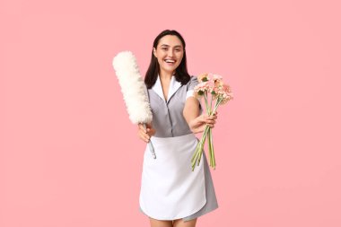 Pembe arka planda çiçek buketi ve toz bezi olan genç kadın hademenin portresi. Uluslararası Kadınlar Günü