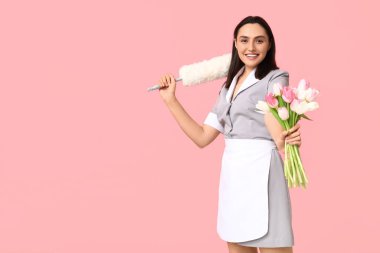 Pembe arka planda çiçek buketi ve toz bezi olan genç kadın hademenin portresi. Uluslararası Kadınlar Günü