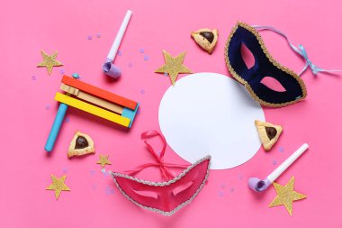 İçinde hamantaschen kurabiyeleri, karnaval maskeleri ve Purim bayramı için pembe arka planda çıngırak olan boş bir kart.