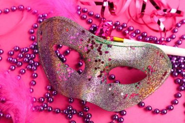 Parti kornalı ve dekorlu karnaval maskesi. Pembe arka planda Mardi Gras kutlaması.