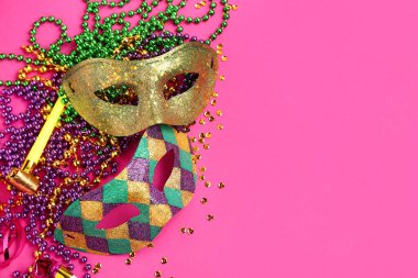 Mardi Gras kutlamaları için parti kornalı ve dekorlu parlak karnaval maskeleri pembe arka planda.