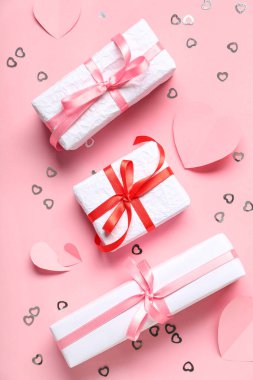 İçinde kağıt kalpler ve pembe arka planda konfeti olan hediye kutuları. Sevgililer Günü kutlaması