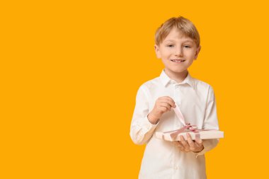 Sarı arka planda hediye kutusu olan şirin bir çocuk. Uluslararası Kadınlar Günü