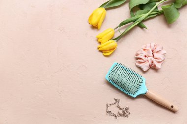 İpek tokalı saç fırçası ve bej arka planda lale çiçekleri