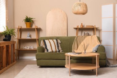 Katlanır perdeli, yeşil kanepeli, lambalı ve kahve masalı güzel bir oturma odası.