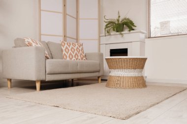 Gri kanepesi, şöminesi, kahve masası ve halısı olan şık bir oturma odası.