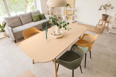 Yemek masası, kanepesi ve bitkileri olan ışık odasının içinde.