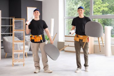 Şık bir odada sandalyeler taşıyan yükleyiciler