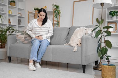 Evde şiddetli karın ağrısı çeken genç bir kadın var.