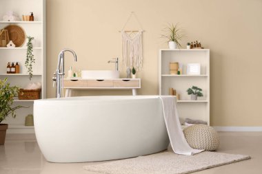 Banyonun içinde havlu, lavabo ve raf üniteleri olan küvet.