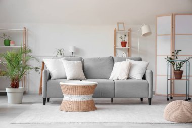 Gri kanepe, masa ve raf üniteleriyle aydınlık oturma odasının içinde.