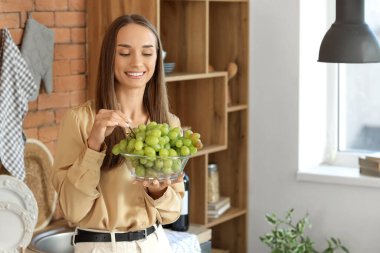 Mutfakta yeşil üzümlü genç bir kadın