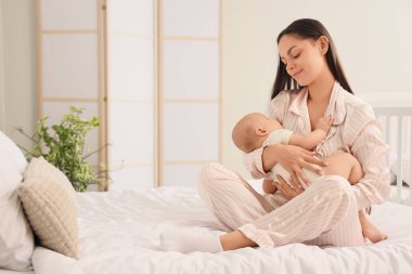 Anne yatak odasında uyumak için bebeğini sallıyor.