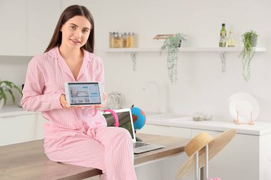 Tablet bilgisayarlı kadın turist mutfaktaki otel odasını ayarlıyor.