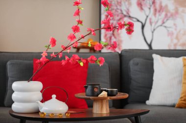 İçinde ağaç dalları olan vazo ve Çin Yeni Yılı için dekore edilmiş oturma odasındaki masada çay.
