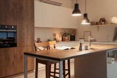 Akşam vakti mutfak masası, tezgahlar ve parlayan lambalar.