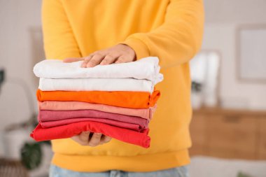 Evde bir yığın temiz giysisi olan yakışıklı genç adam, yakın plan.