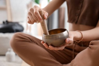 Tibet şarkı kasesi olan genç bir kadın evde meditasyon yapıyor, yakın plan.