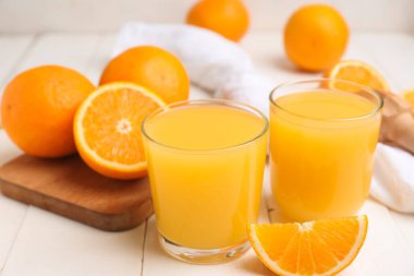 Beyaz ahşap masada portakallı bir bardak lezzetli meyve suyu.