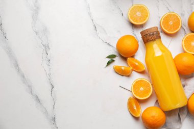 Mermer arka planda taze portakallı bir şişe lezzetli meyve suyu.