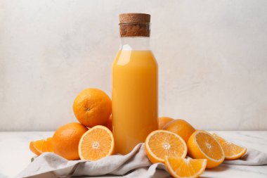 Taze portakallı ve arka planda peçeteli bir şişe lezzetli meyve suyu.