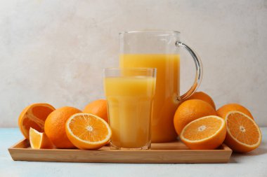 Portakallar ve hafif arka planda bir sürahi lezzetli meyve suyu.